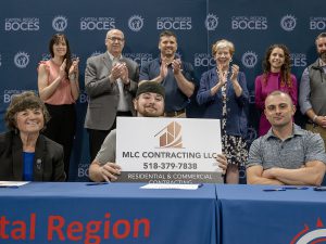 Student holds sign with business partner and digniteries