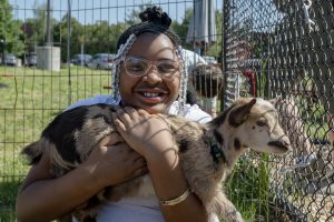 A young student holds onto a baby goat during the petting zoo at Airline Drive Academy.