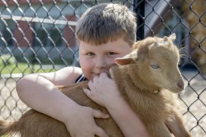 A young student holds onto a baby goat during a petting zoo at Airline Drive Academy.