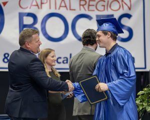 Student shakes hands while receiving his diploma
