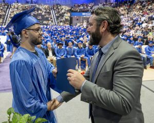 Student receiving diploma in front of a large crowd