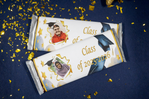 A close up photo of chocolate bars with photos of Airline Drive Academy graduates on the cover paper.