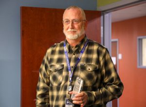 A man stands in a conference room holding an award
