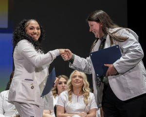 grad smiles while shaking hands