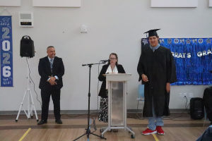 Maywood Principal Gabe Barbato and Teacher Catherine Rickert stand together to present Rakisaiah Austin with his graduation certificate.