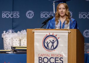 Trista Smi stands behind a podium speaking at a ceremony