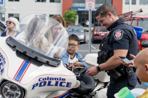 A student sits on a police motorcycle with the help of teachers and a local police officer.