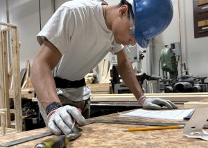 Student in hard hat looks at blue prints