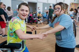 Two students hold hands while dancing together at Maywood Academy's 80s dance party.