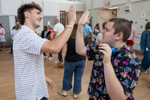 A student gives a high five to his teaching assistant during the 80s dance party at Maywood Academy.