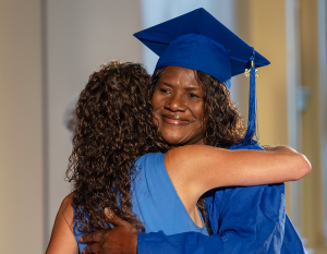BOCES Assistant District Superintended hugs an adult education program graduate. The photo is taken from the female graduate's perspective and she is smiling.