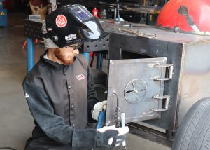 Adult, hood raised, welding