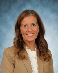 A headshot of Lauren Morley. She is wearing a tan jacket and a white blouse