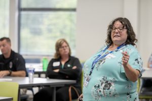 A woman is speaking at the head of a conference room