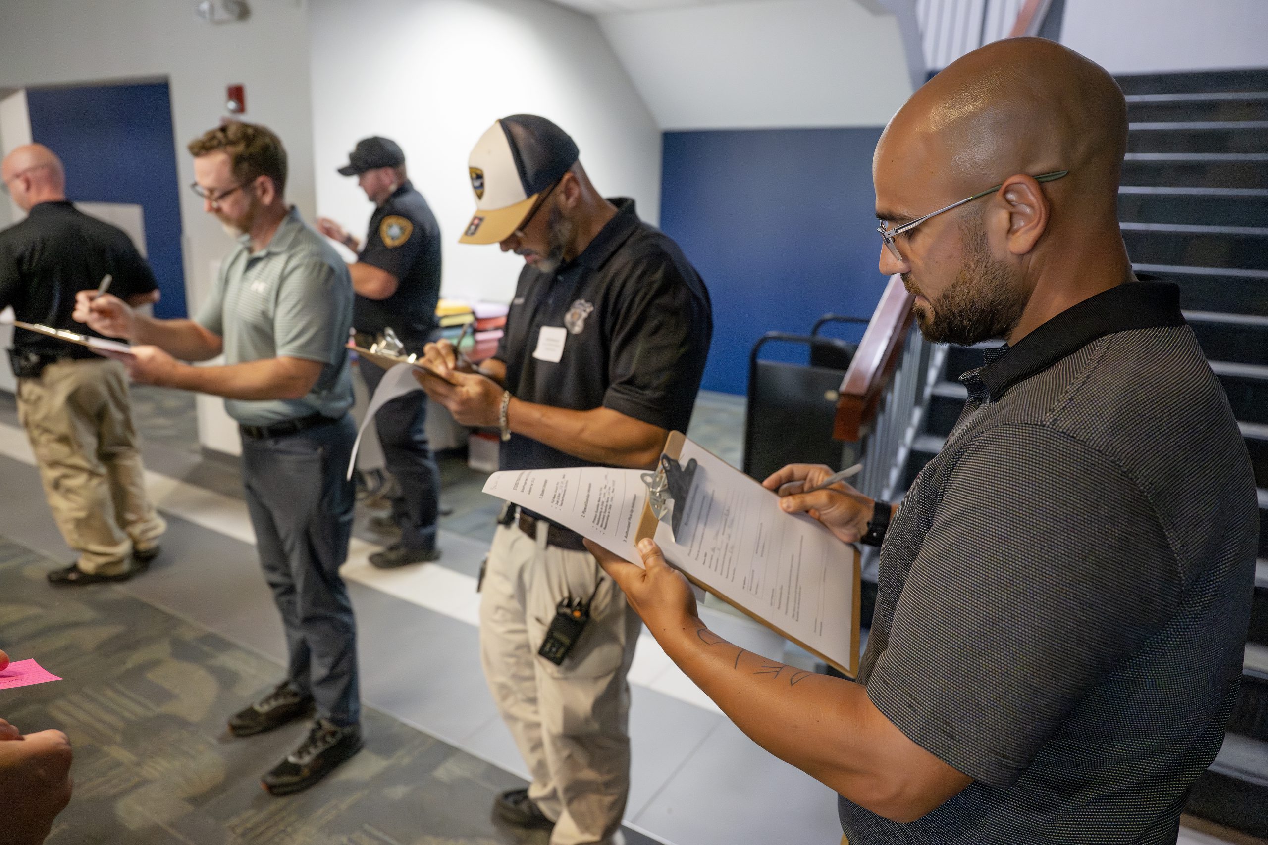 Several people are working, writing on papers on clipboards