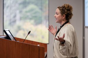 A woman is speaking at a podium. She is gesturing