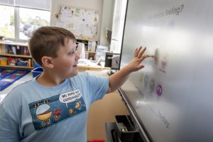 A young student at Maywood Academy   makes a selection on the touch screen on the first day of school. 