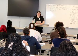 Teacher behind a podium facing dozens of students