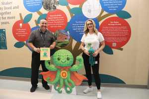 Maywood Academy Principal Gabriele Barbato holds a copy of Ocho the Brave Octopus alongside and Author Jennifer Hendricks-Fogg who is holding a green Ocho the Octopus toy.