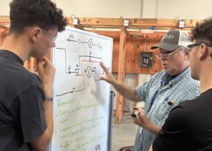 teacher and 2 students at a white board