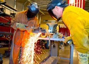 A student welds as a teacher looks closely