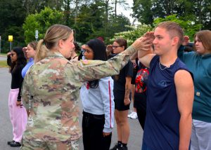 soildier fixes the hand of a student saluting 