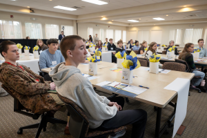 A wide range photo of students seated at desks during the Board of Education Member Training.