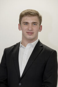 A head shot of a student wearing a dark blazer and a white button down shirt