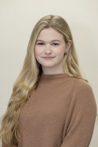 A head shot of a student wearing a brown sweater